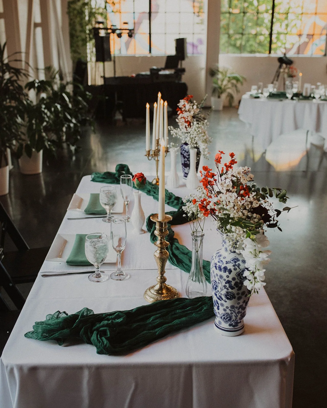 Wedding sweetheart table featuring blue-and-white floral vases, brass candlesticks, greenery, and elegant reception decor at The Castaway in Portland.