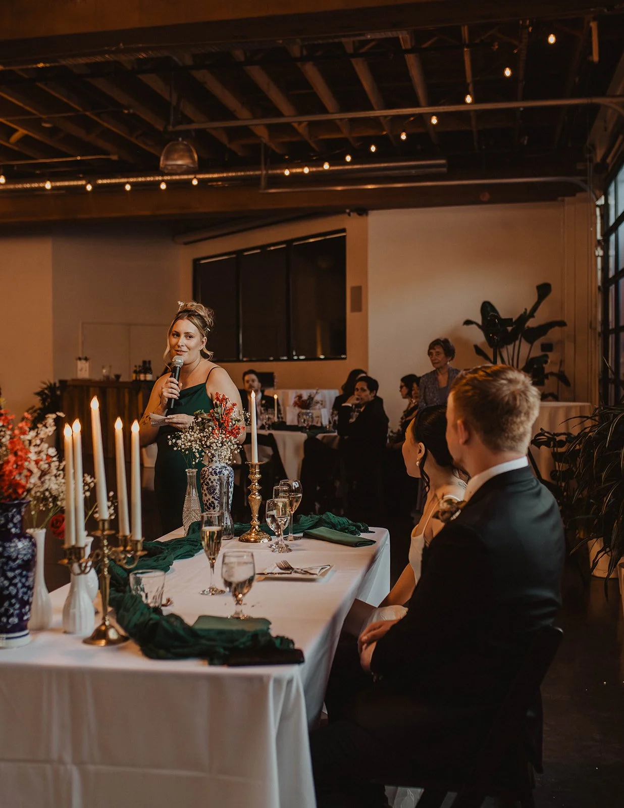 Wedding guest gives a reception toast while the bride and groom listen from their sweetheart table at The Castaway in Portland.