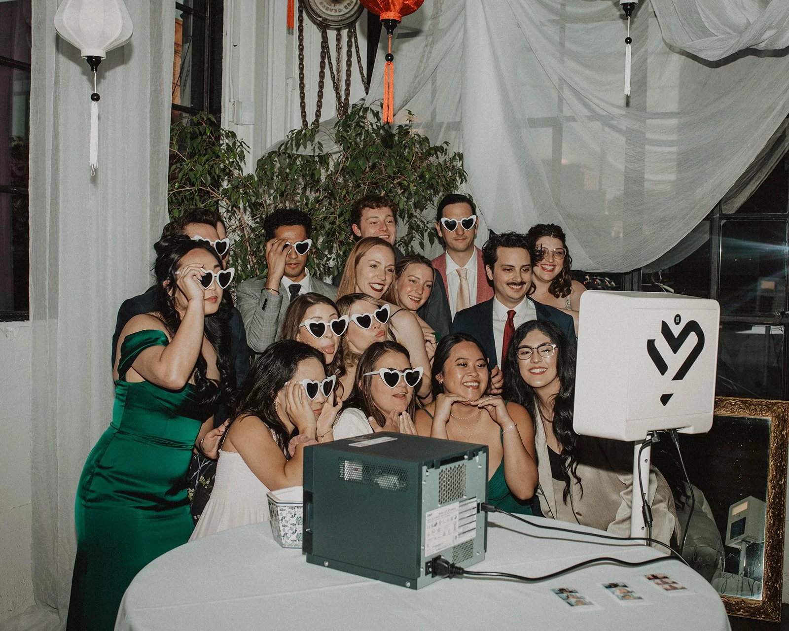 Wedding guests wearing heart-shaped sunglasses pose together at a photo booth during a reception at The Castaway in Portland.