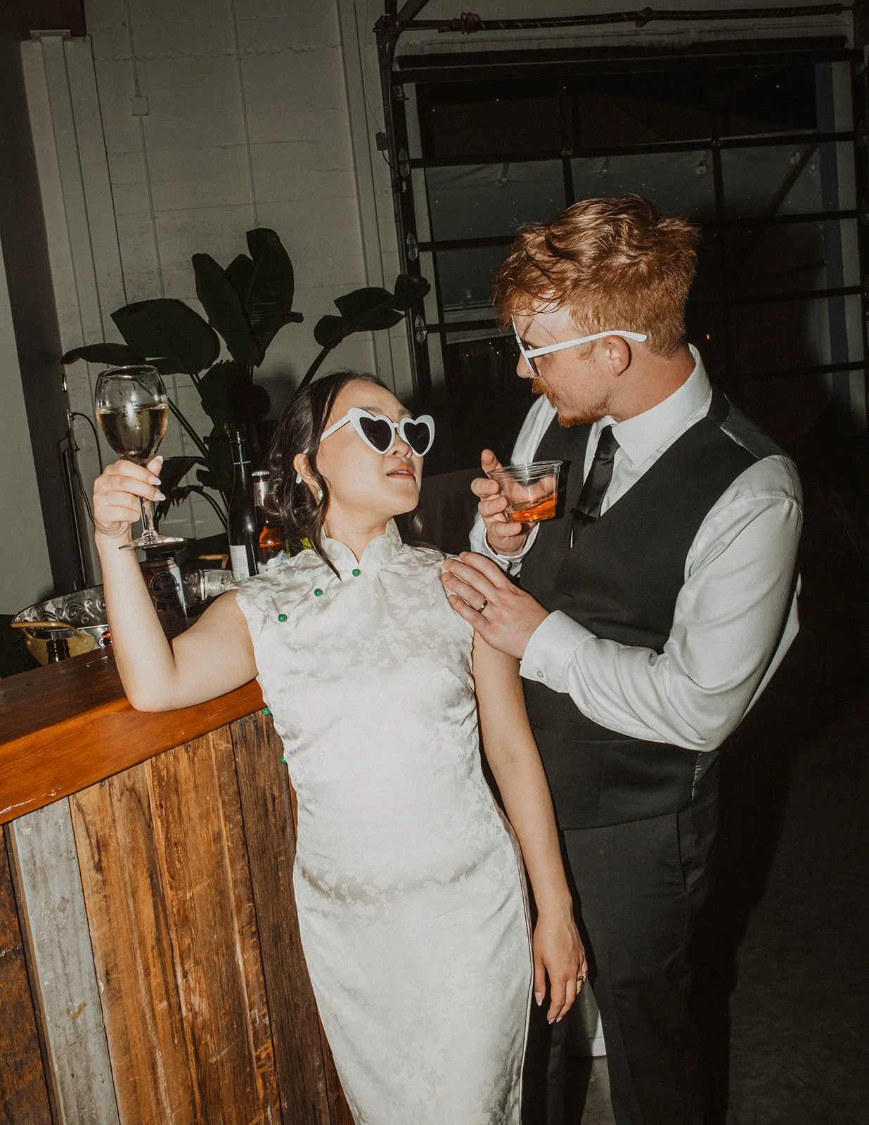 Bride and groom share a playful moment with drinks in hand while posing near the reception bar at The Castaway in Portland.