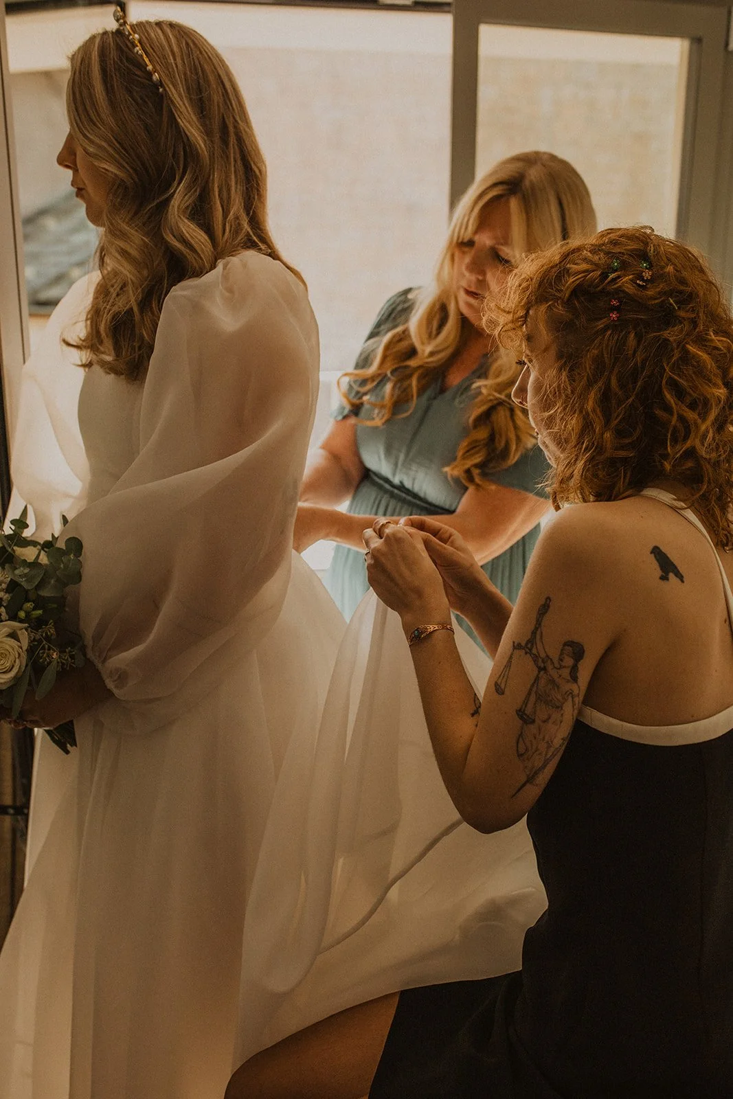 Family members helping the bride with the final details of her wedding dress before her intimate ceremony at Villa del Balbianello.