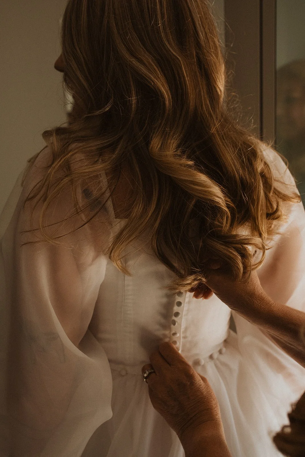 Close-up of a bride's wedding dress being buttoned during the getting-ready moments before a Lake Como elopement.