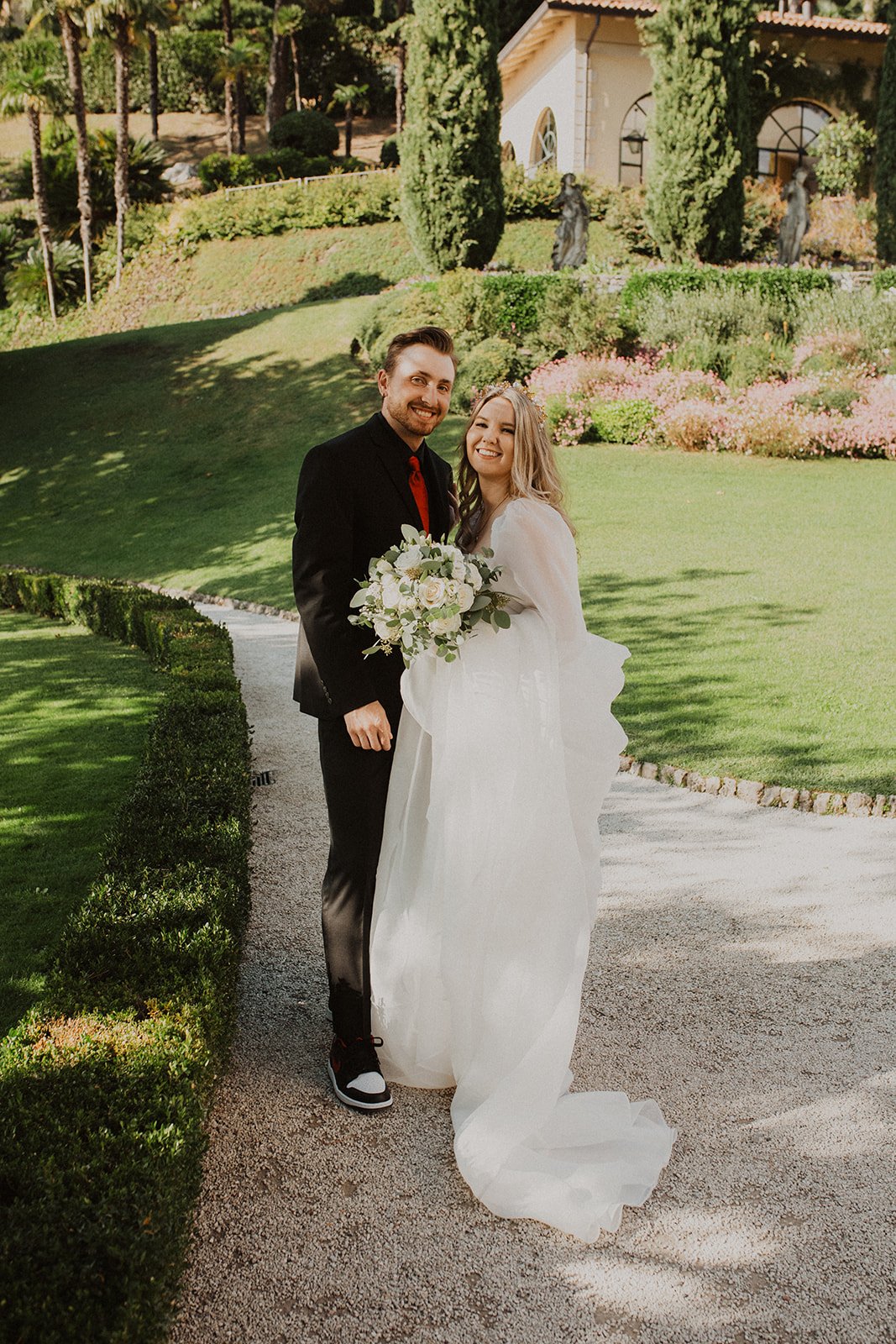 Newlyweds smiling together in the formal gardens at Villa del Balbianello following their Lake Como elopement.