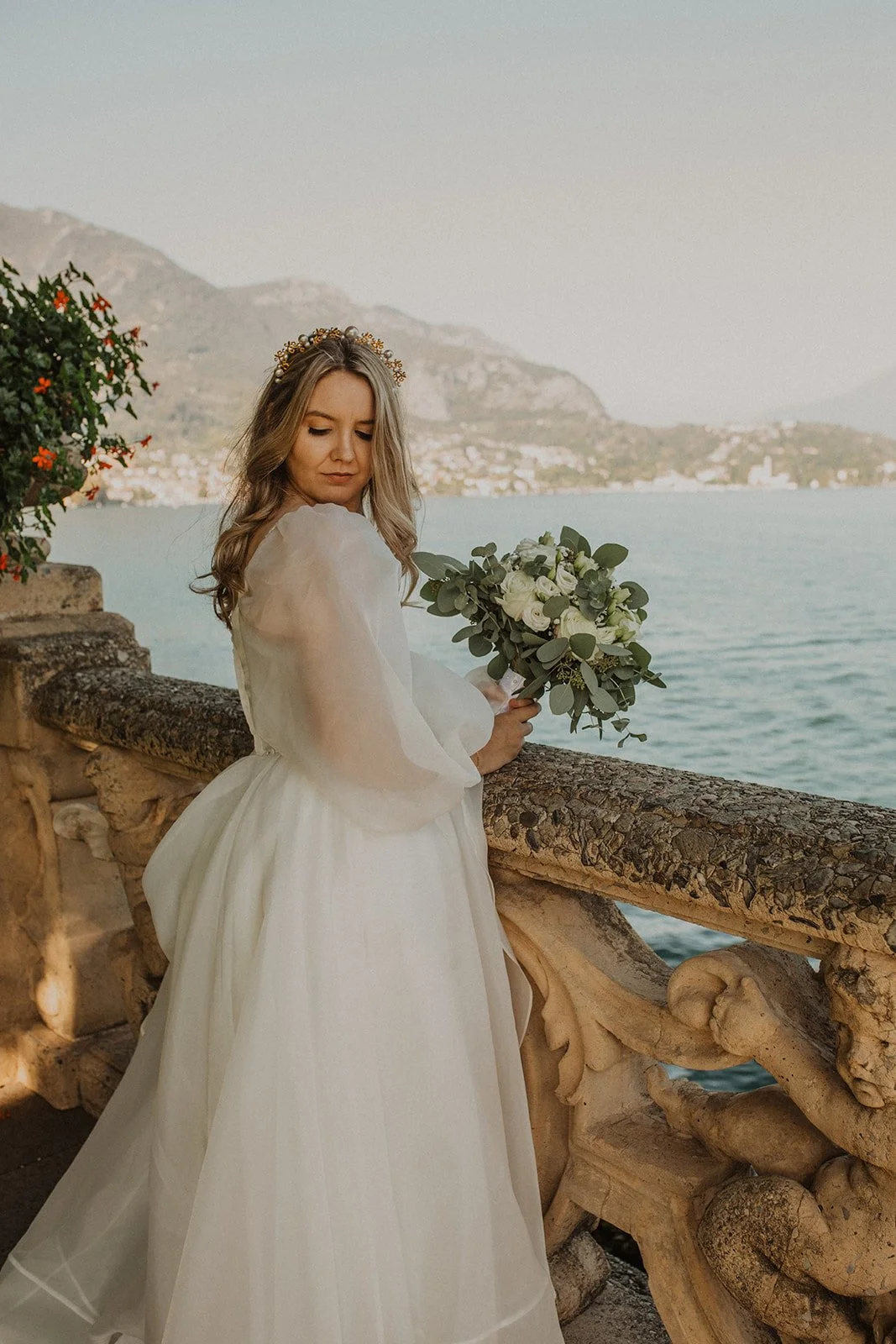 Bride holding her bouquet while overlooking Lake Como from the historic terrace at Villa del Balbianello before her intimate elopement ceremony.