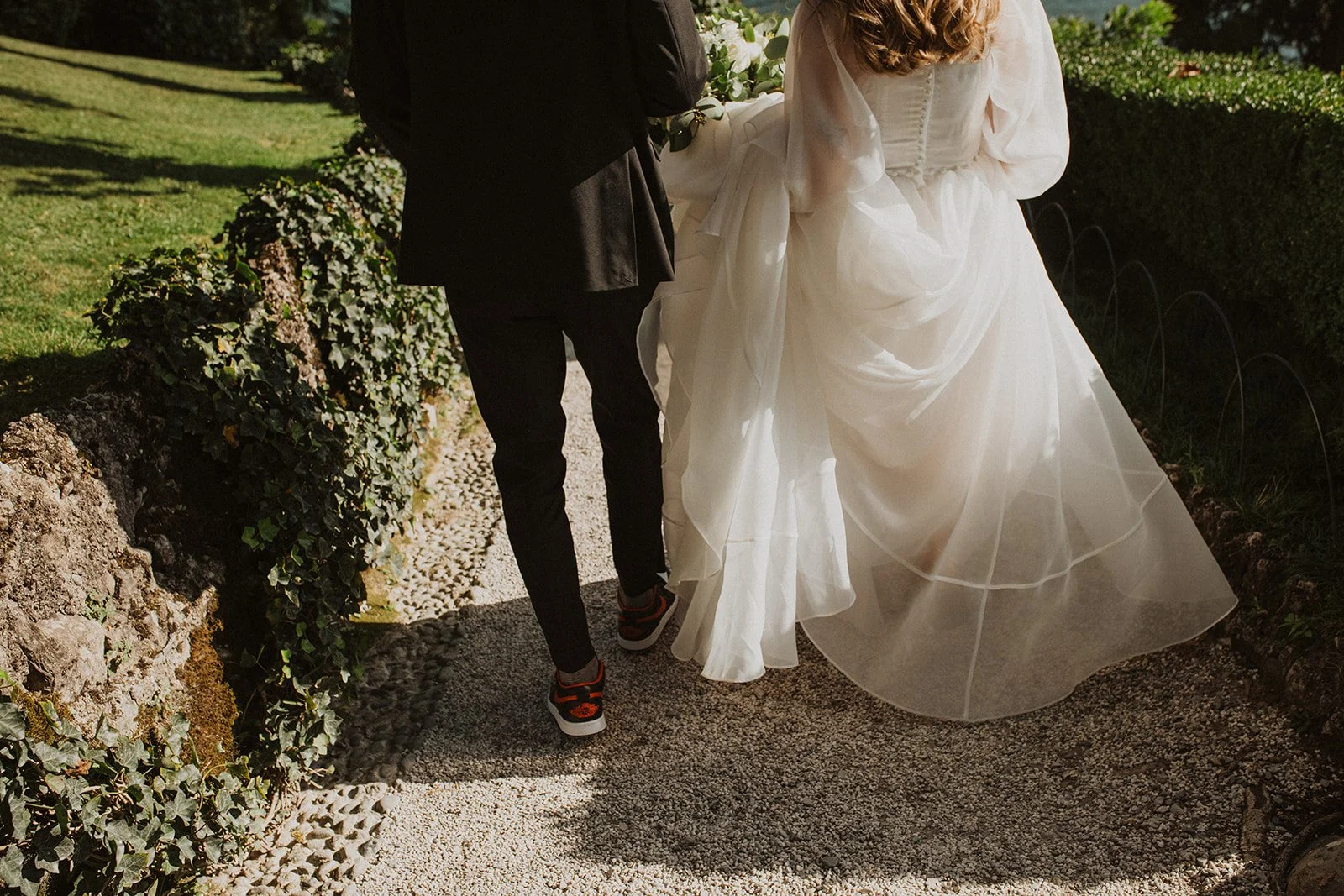 Bride and groom walking hand in hand along a garden path at Villa del Balbianello after their Lake Como wedding.