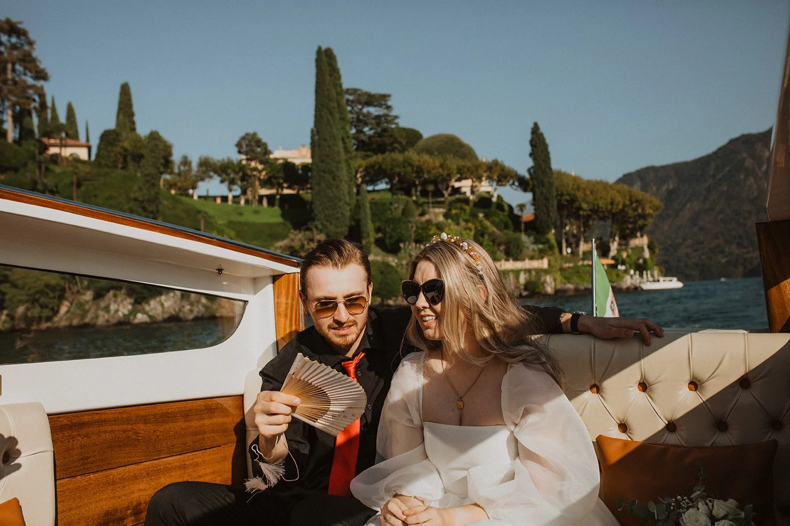 Newlyweds enjoying a scenic boat ride across Lake Como while sharing a quiet moment together after their wedding ceremony.