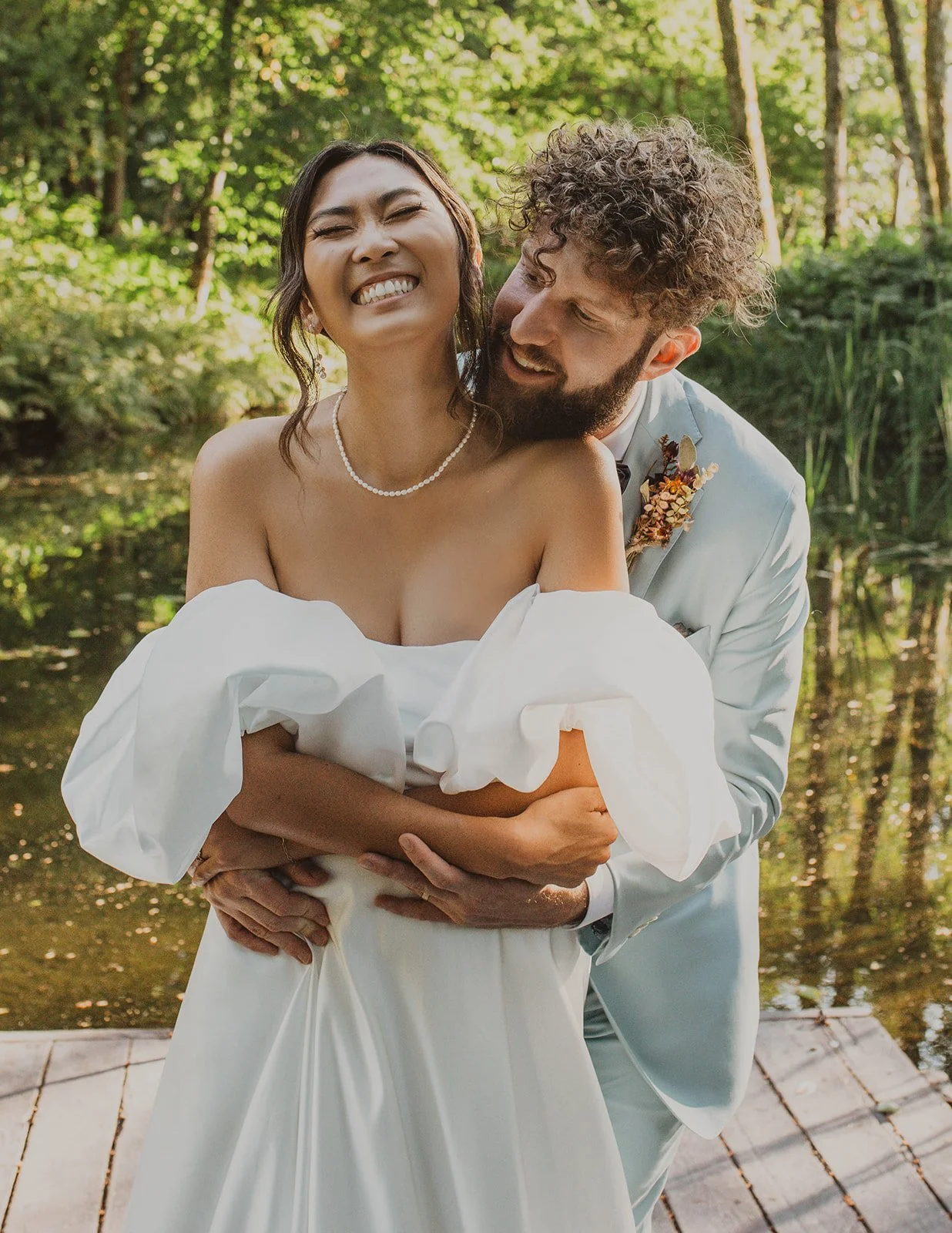 Groom hugging the bride from behind as they laugh together during candid wedding portraits at Bridal Veil Lakes in Oregon.