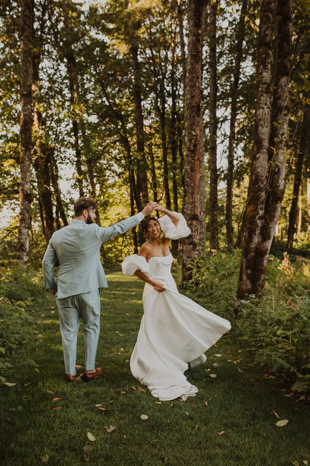 Groom twirling the bride through a wooded path during playful wedding portraits at Bridal Veil Lakes in Oregon.