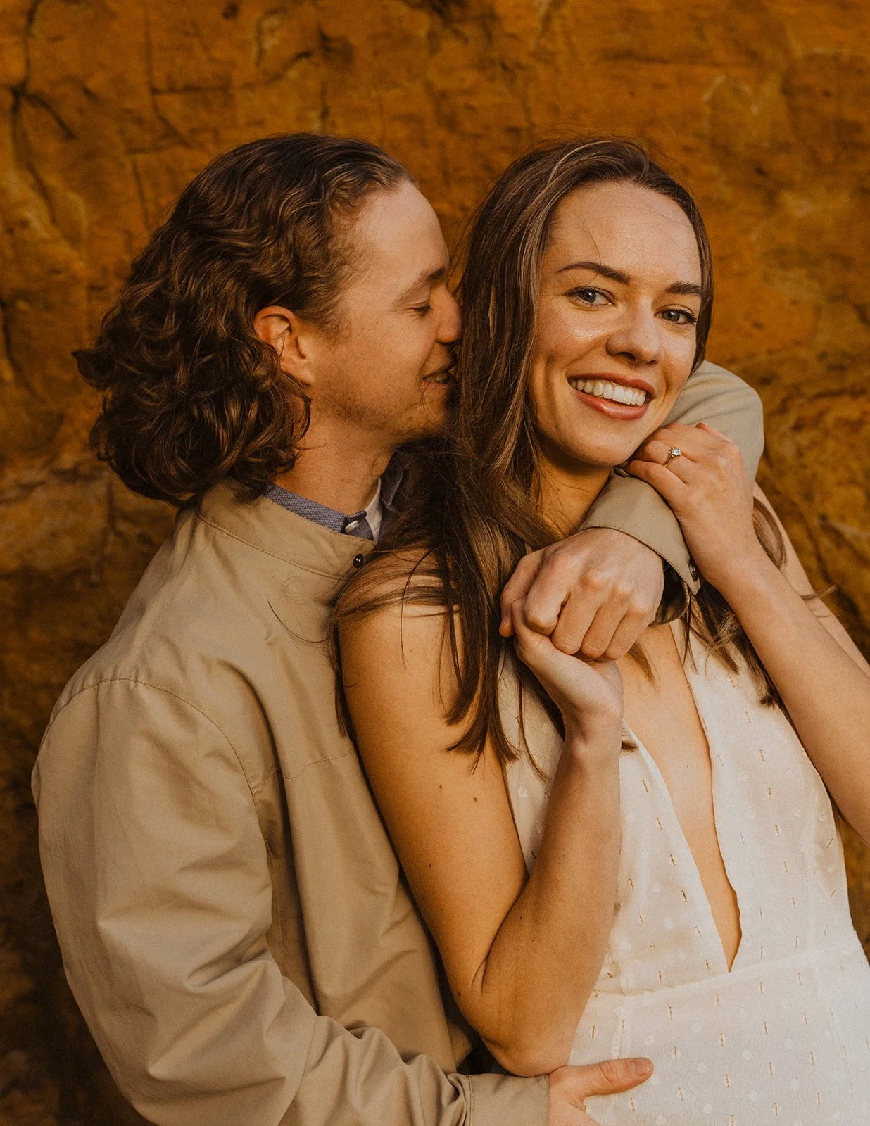 Lucas hugs Miranda from behind during their documentary-style engagement session at Cape Kiwanda