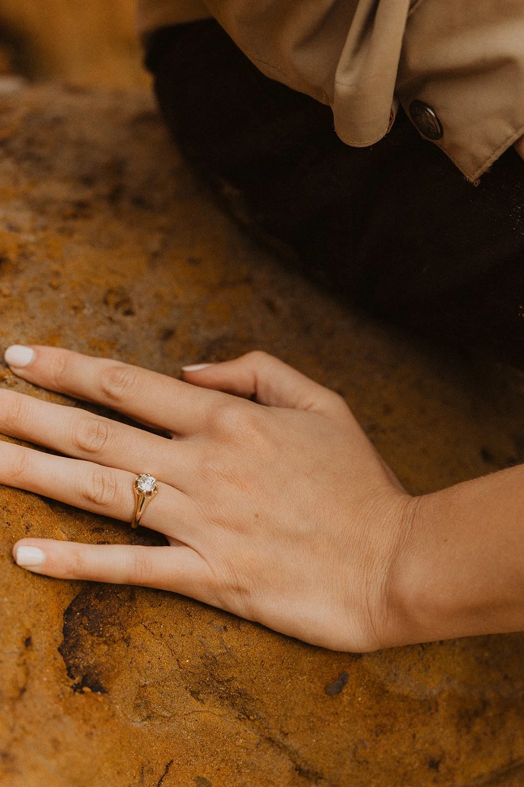 Close-up photo highlighting Miranda's engagement ring as she rests her hand on Lucas during their Cape Kiwanda engagement session