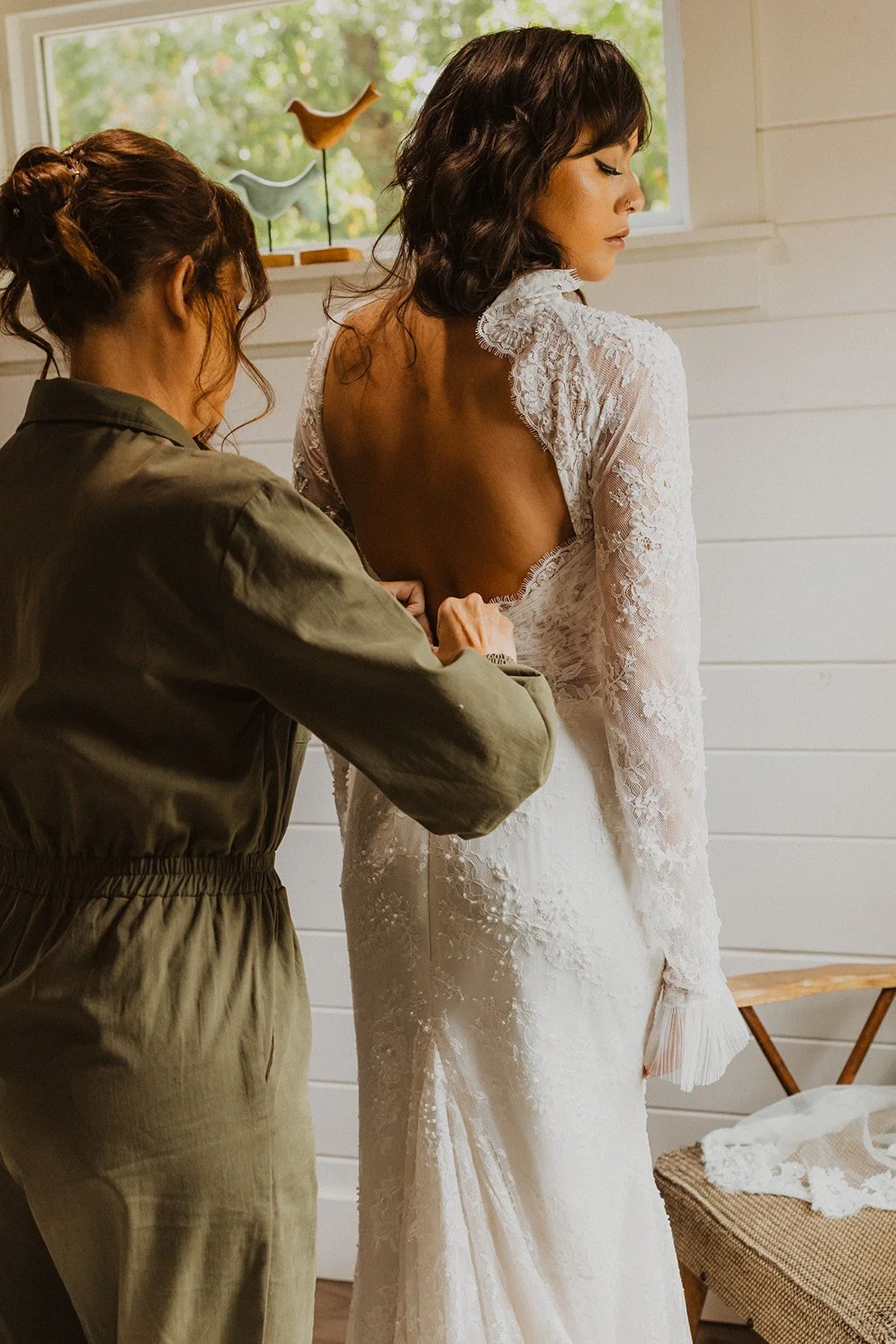 Bride having the back of her lace wedding dress fastened while getting ready at Bright Morning Farm.