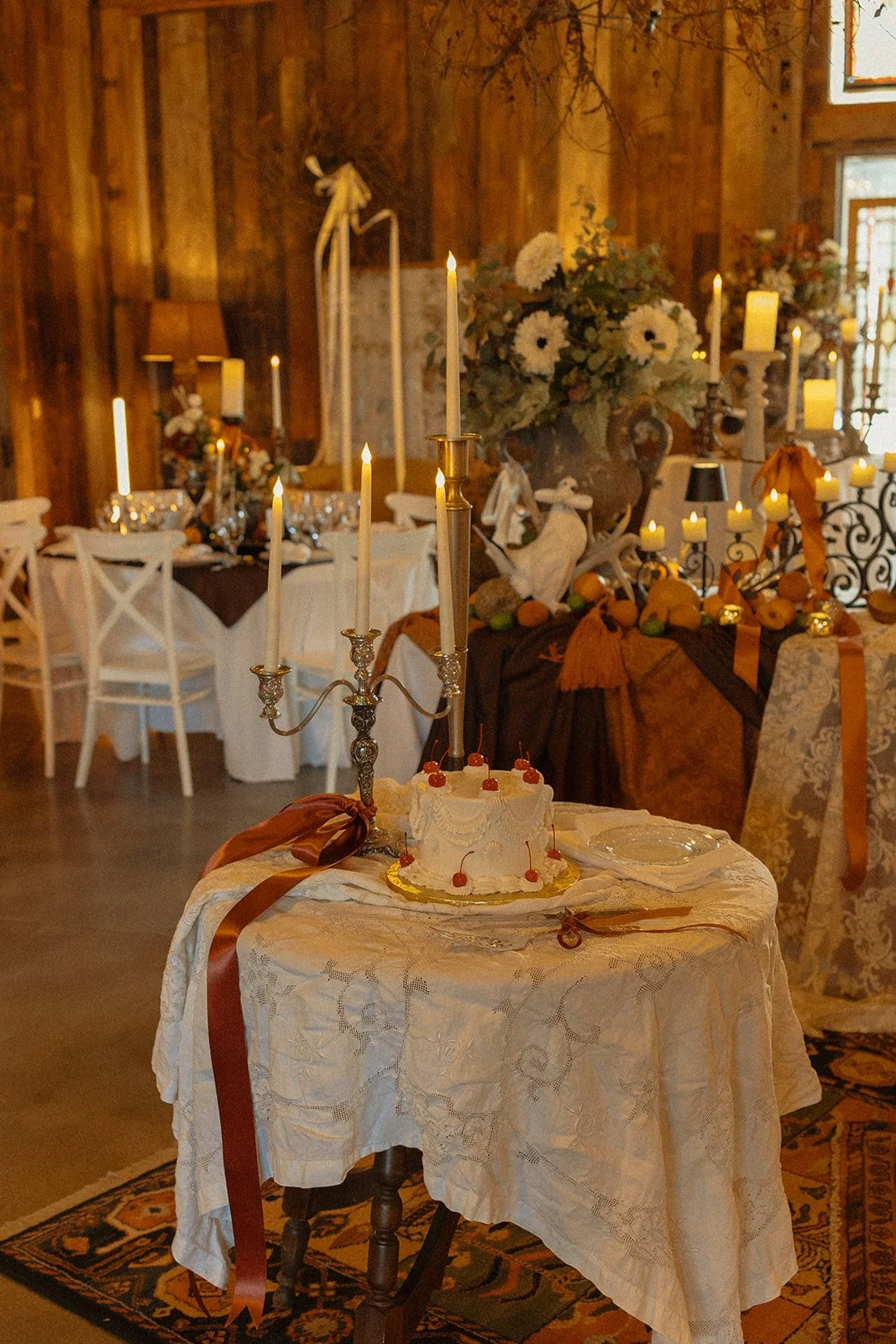 Vintage-inspired wedding cake displayed with candlelight and fall reception décor inside Bright Morning Farm.