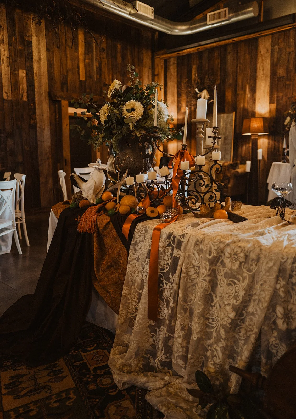 Vintage-inspired sweetheart table decorated with candles, florals, fruit, layered fabrics, and nature-inspired details at Bright Morning Farm.