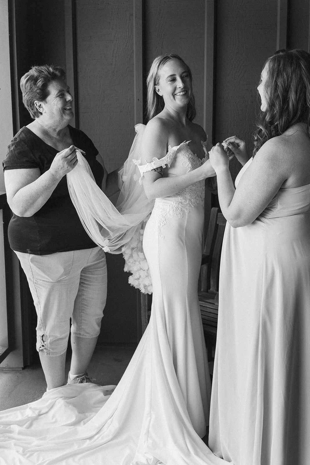 Bride smiling while family members help adjust her veil before the ceremony at Skamania Lodge.