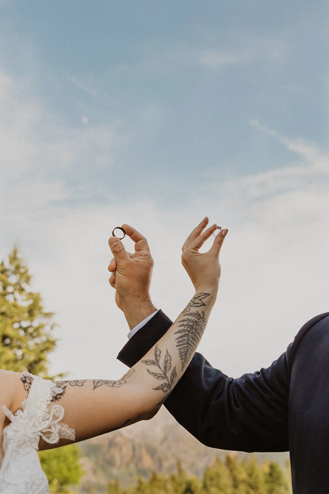 Bride and groom holding their wedding rings toward the sky during portraits at Skamania Lodge.