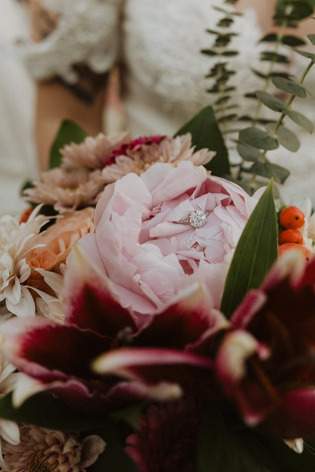 Engagement ring resting inside a pink and burgundy wedding bouquet at Skamania Lodge.