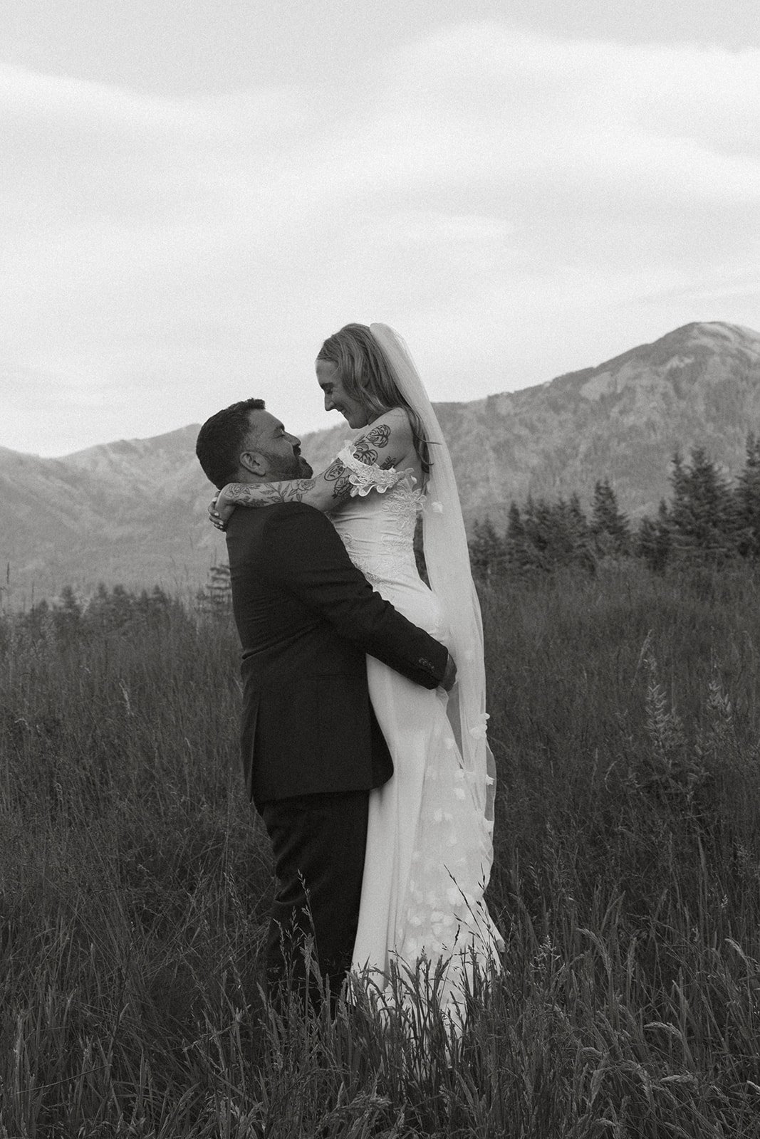 Bride and groom embracing in a meadow with Columbia River Gorge mountains behind them during portraits at Skamania Lodge.