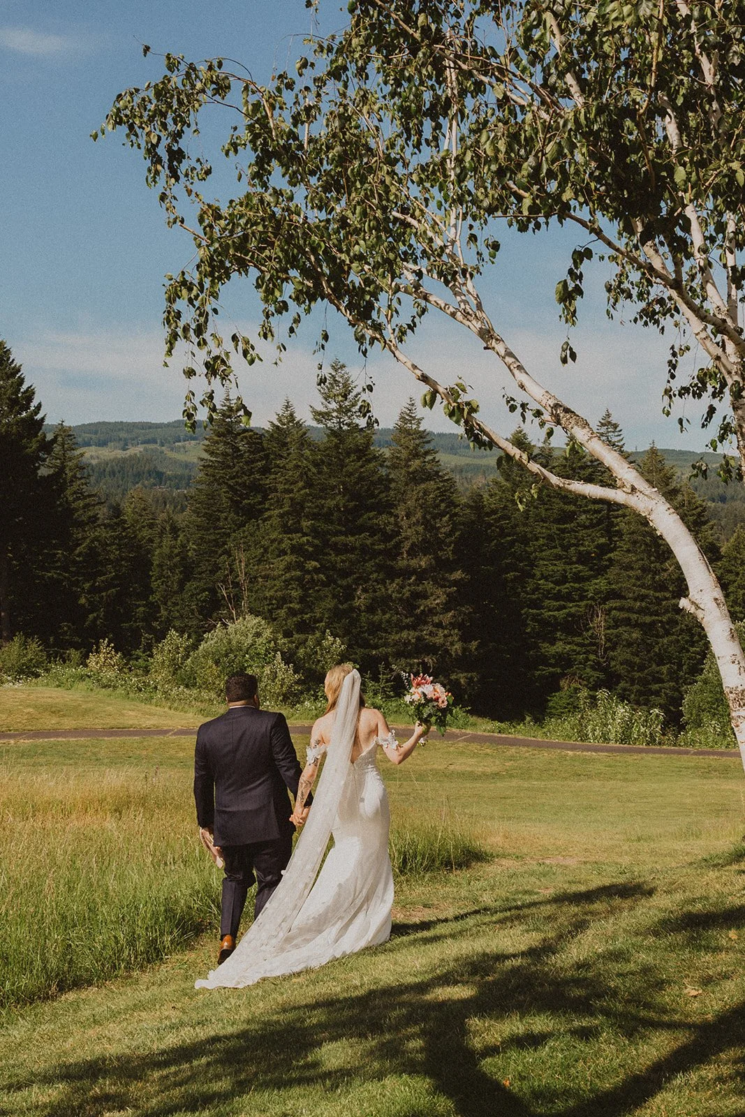 Newly married couple walking hand in hand across the Skamania Lodge grounds after their ceremony.