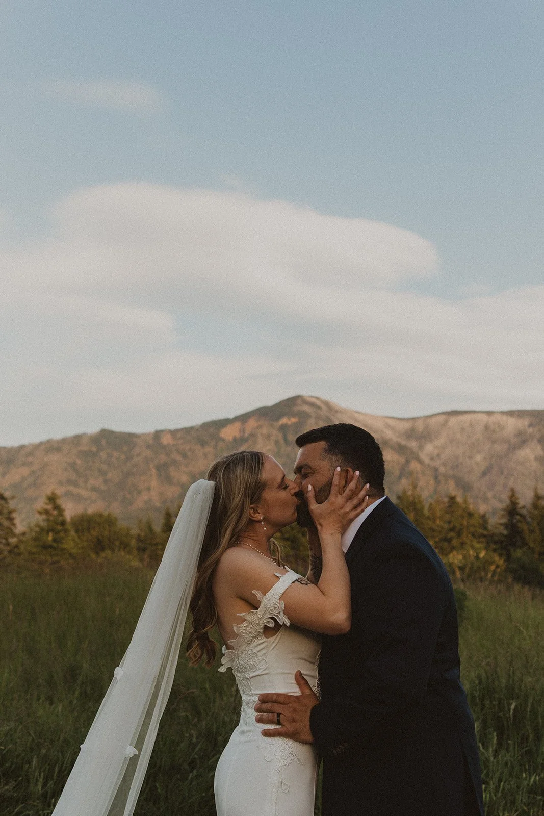 Bride and groom sharing a kiss during sunset portraits with mountain views at Skamania Lodge.