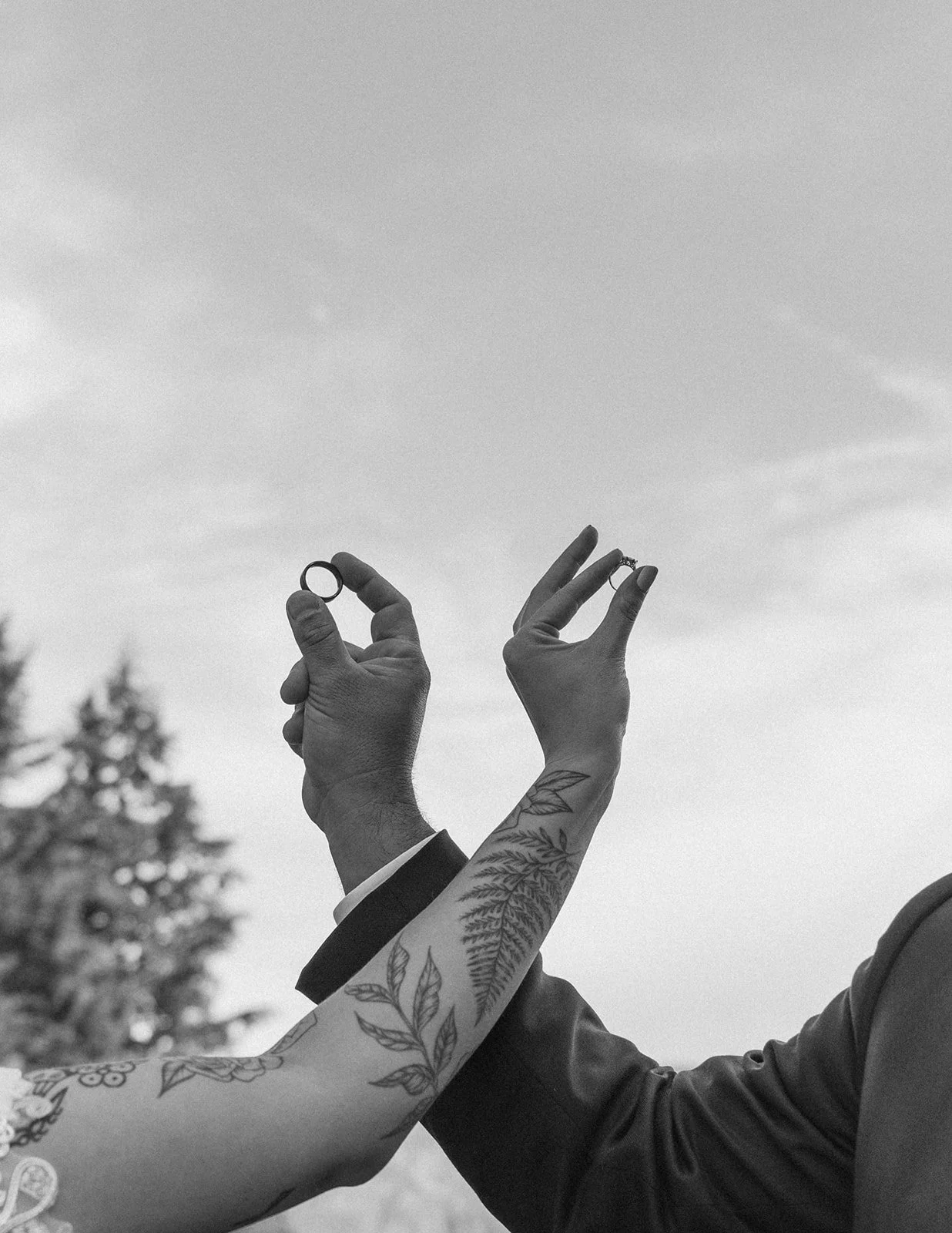 Couple holding their wedding rings toward the sky in a black-and-white photo at Skamania Lodge.