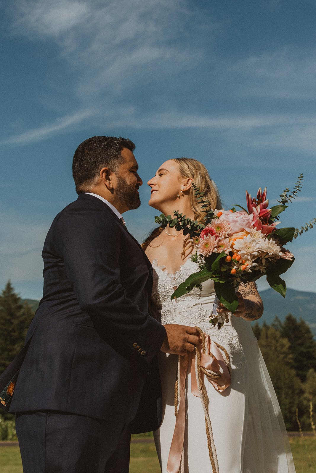 Newlyweds smiling together during golden hour portraits with the Columbia River Gorge in the background.