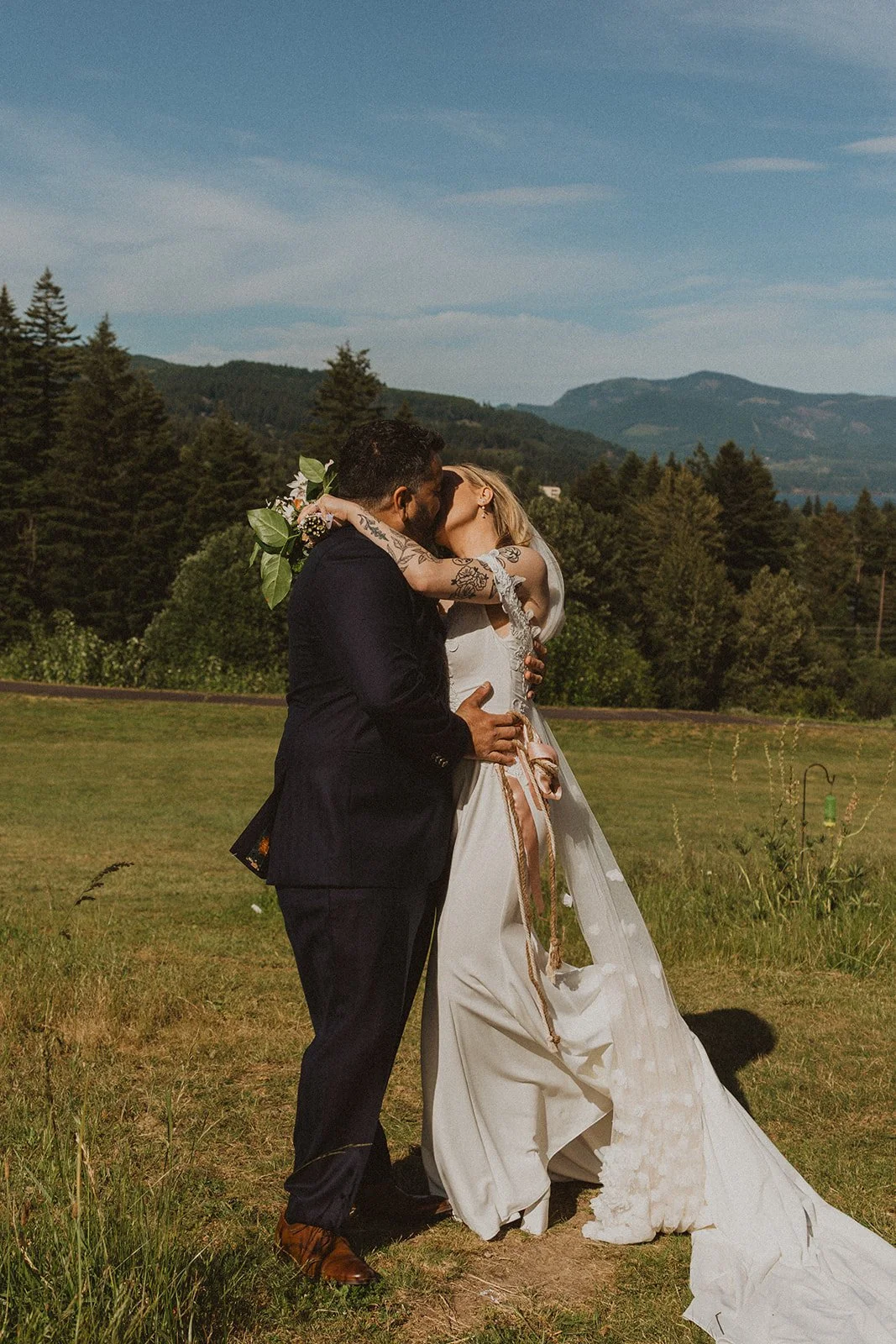 Newlyweds sharing a kiss during wedding portraits overlooking the Columbia River Gorge at Skamania Lodge.
