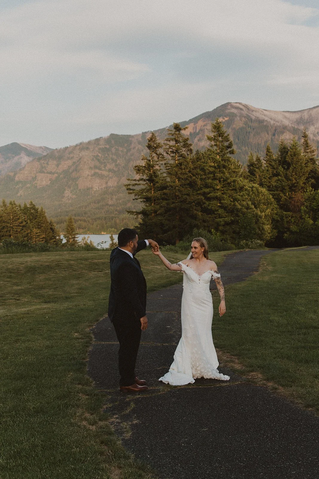 Bride twirling beneath her groom's hand during sunset wedding portraits at Skamania Lodge.
