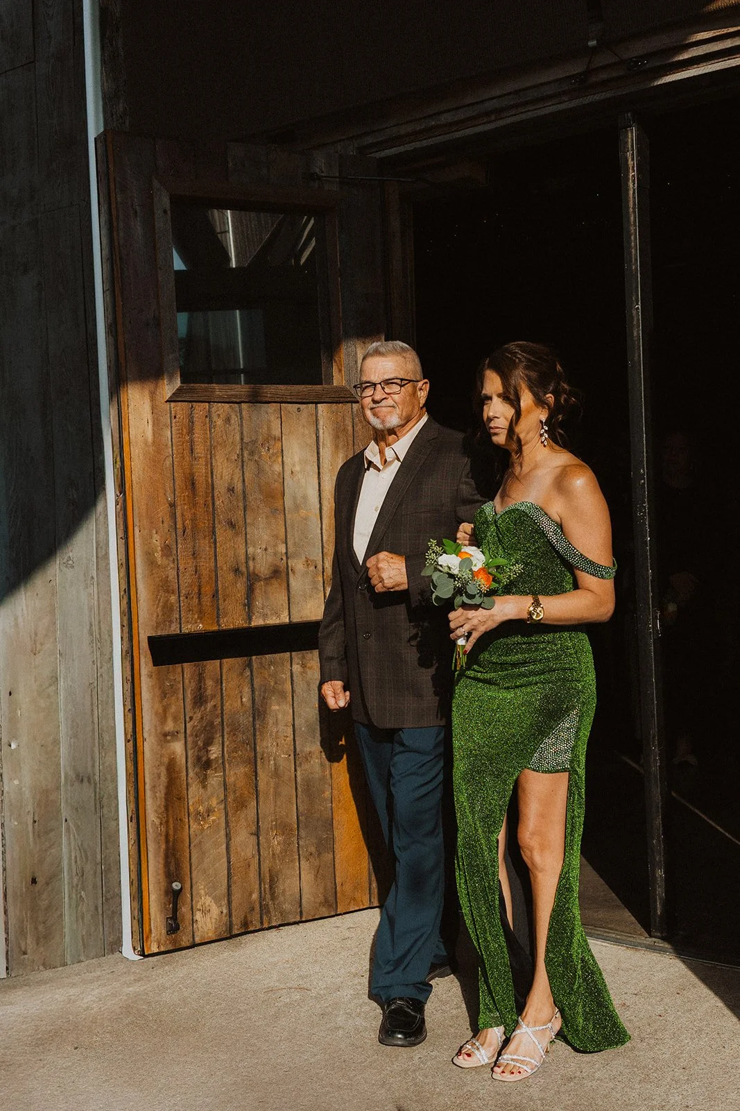 Family member in a green gown walking down the aisle with an older gentleman during an outdoor wedding ceremony at Bright Morning Farm.