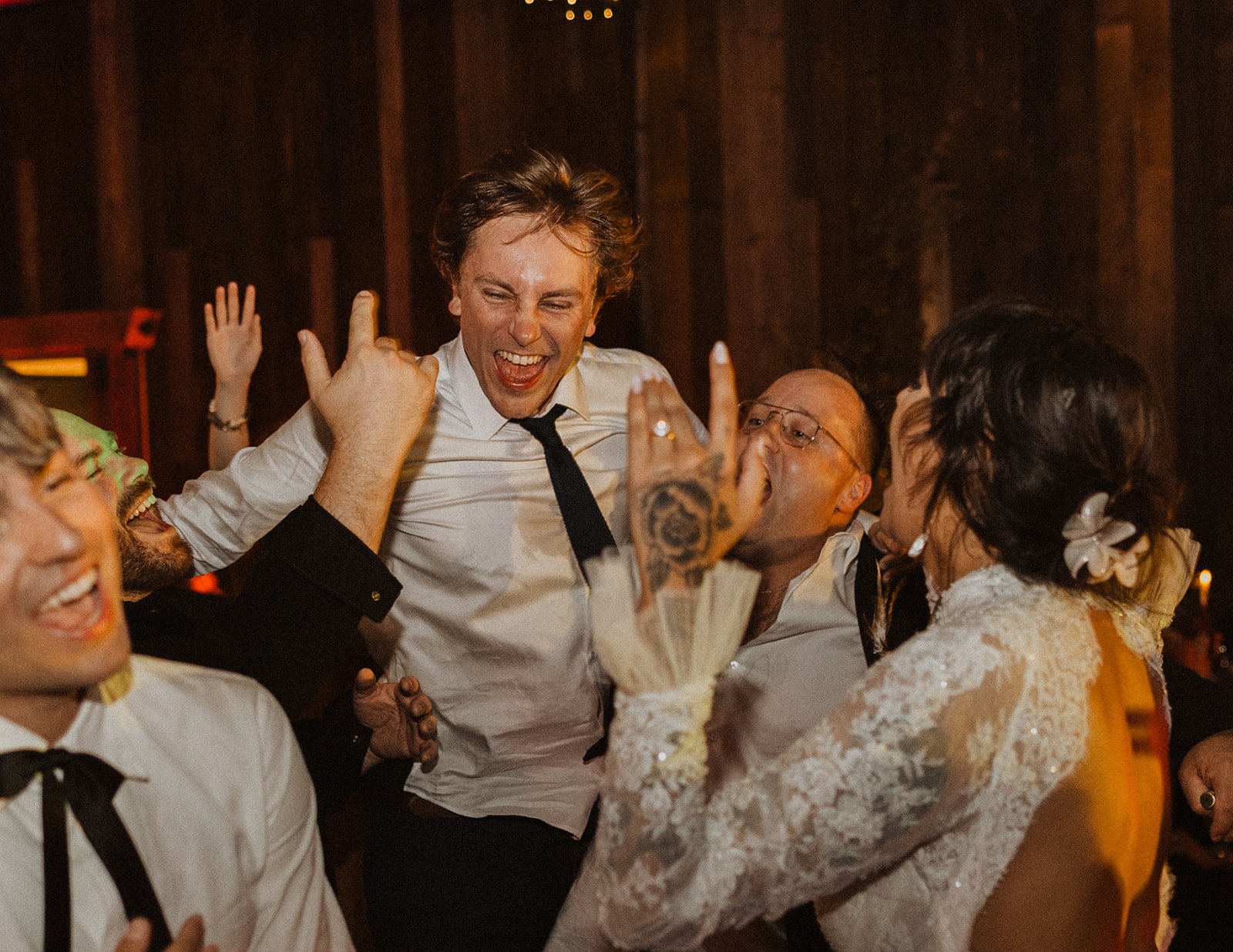 Wedding guests cheering and dancing together on the reception dance floor at Bright Morning Farm during an energetic evening celebration.