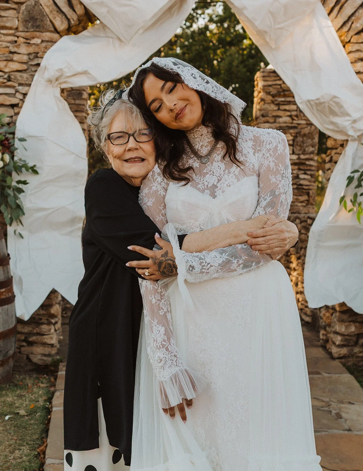 Bride sharing a hug with her grandmother after the ceremony beneath the stone wedding arch at Bright Morning Farm.