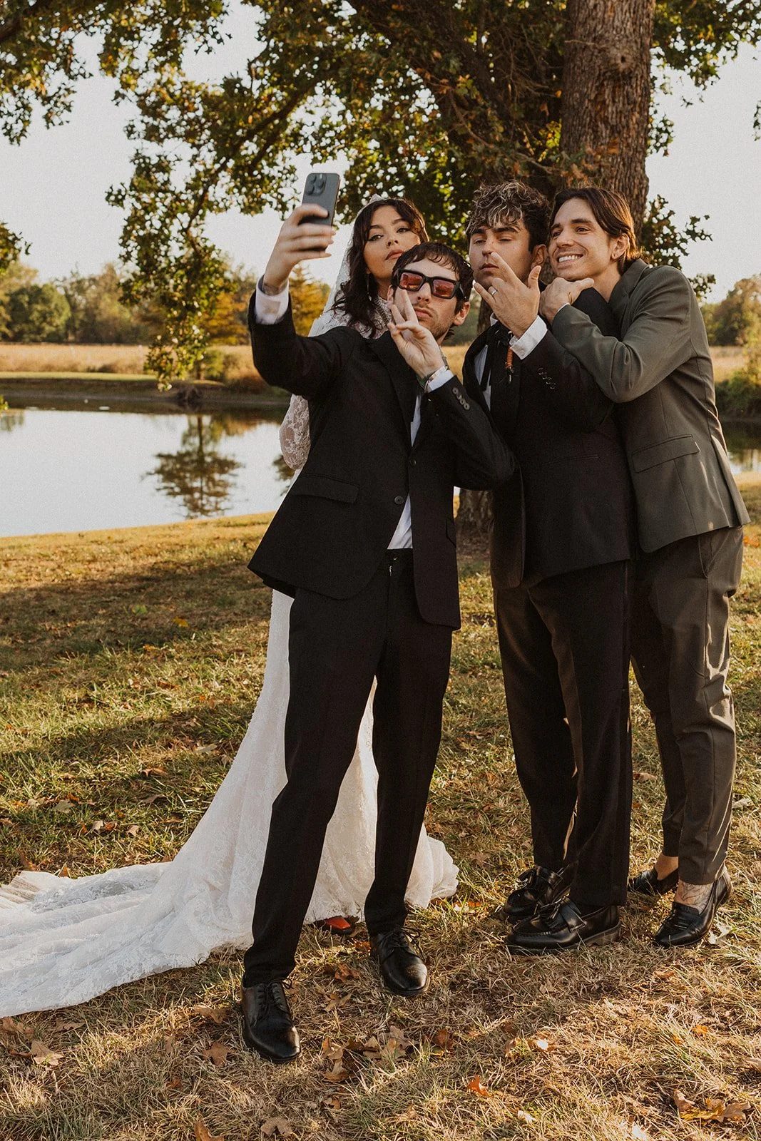 Newlyweds taking a selfie with friends beside the pond during cocktail hour at Bright Morning Farm.
