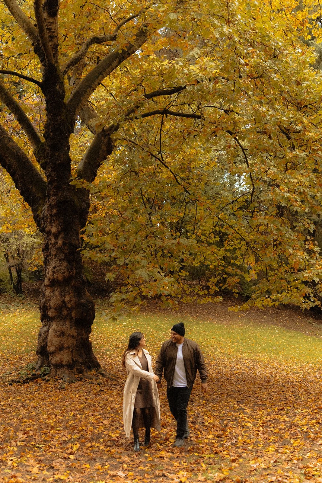 Couple walking a leaf-covered path at Laurelhurst Park in autumn