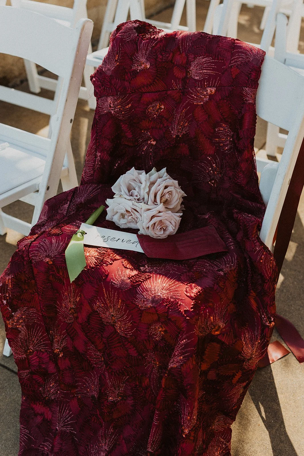 Deep red fabric and florals on a chair at an Oregon vineyard wedding