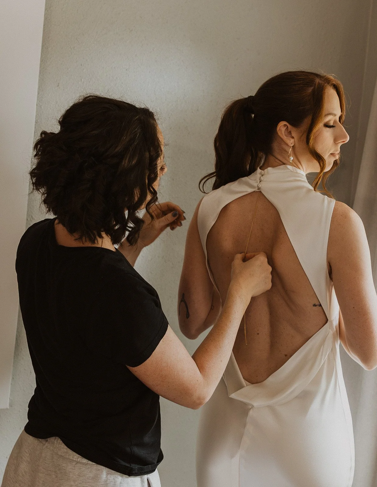 Mother fastening the back of the dress before an Oregon winery wedding