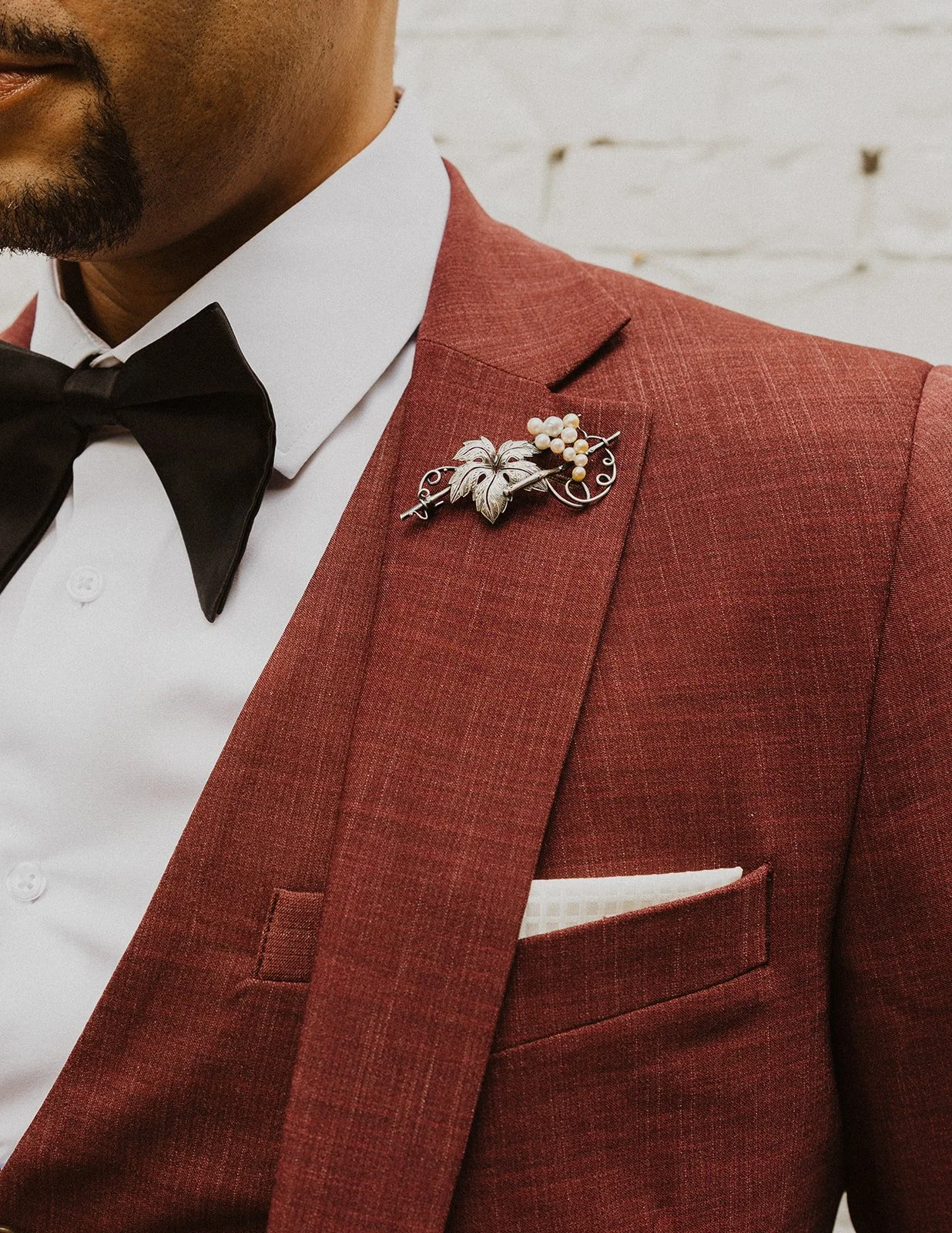 Pearl grape cluster boutonniere pinned to a burgundy lapel at an Oregon winery wedding
