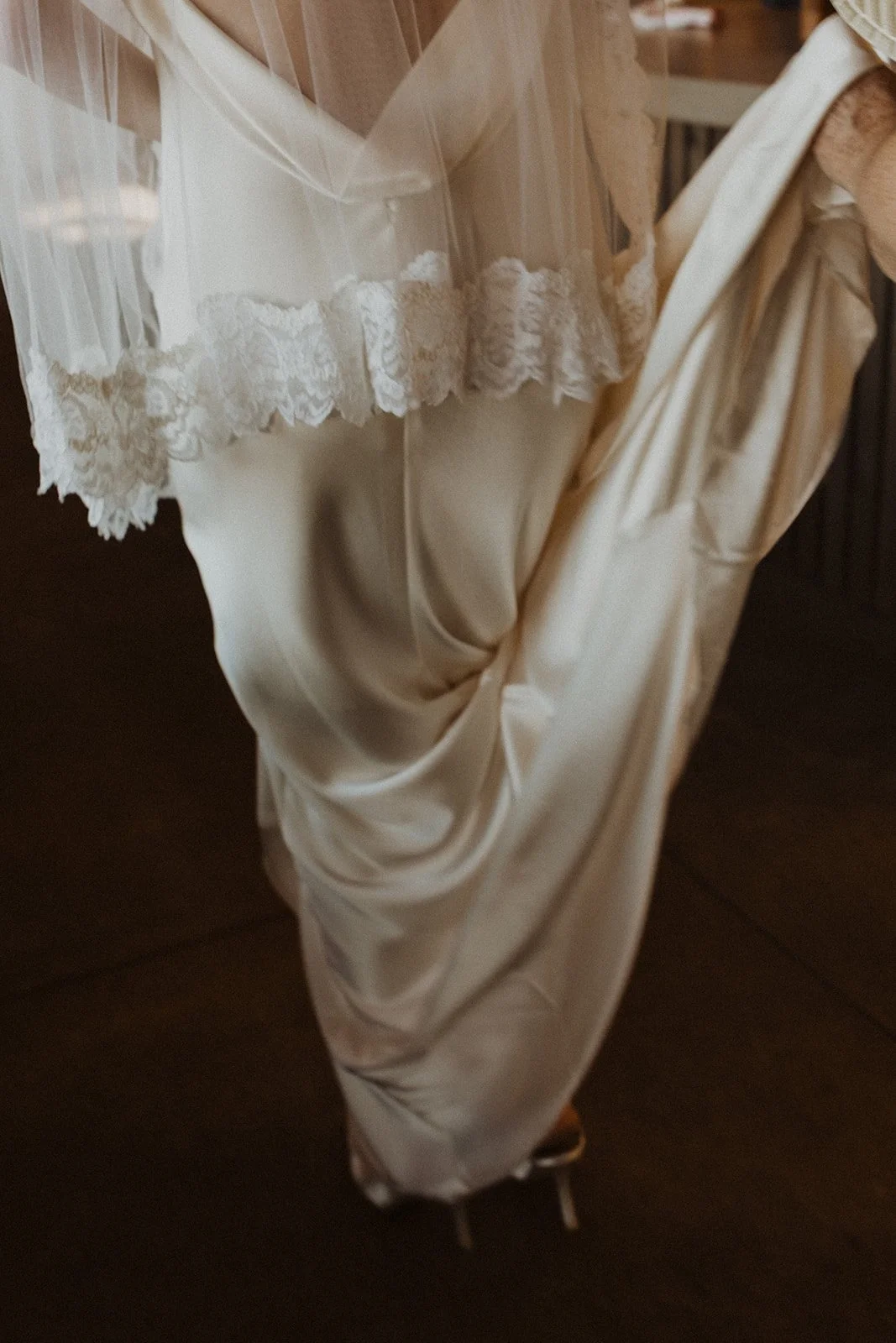 Gathering a satin skirt and lace-edged veil before walking out