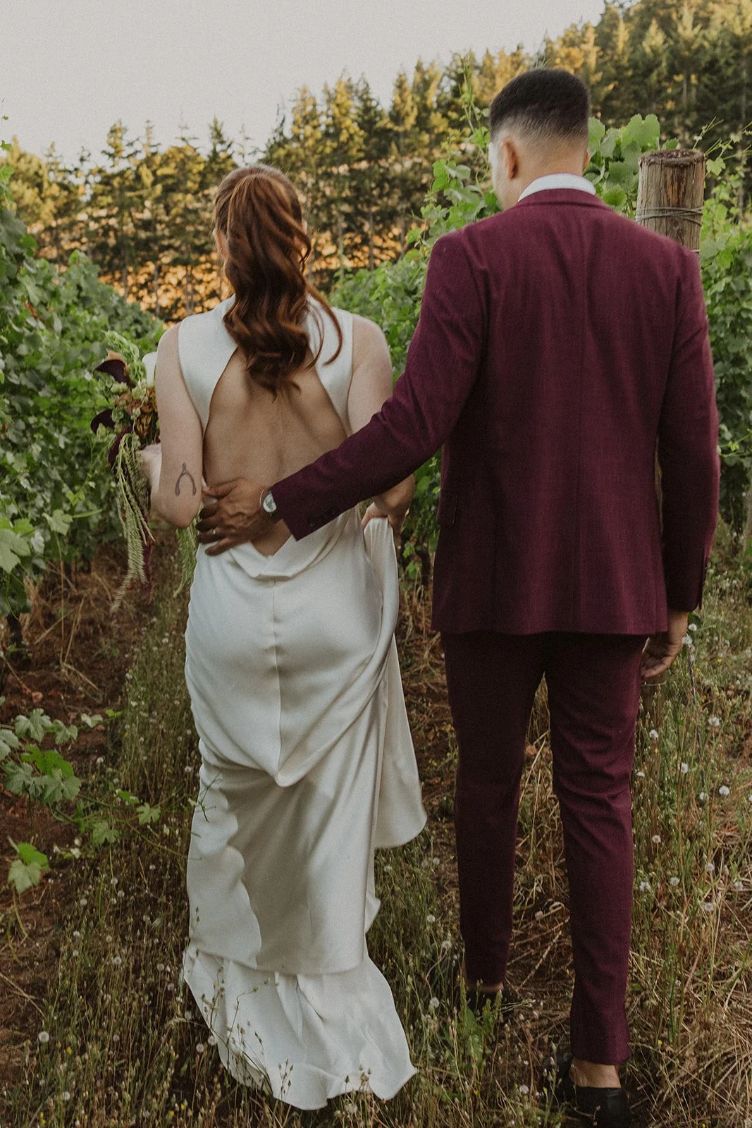 Walking down the aisle toward the rows at an Oregon vineyard wedding