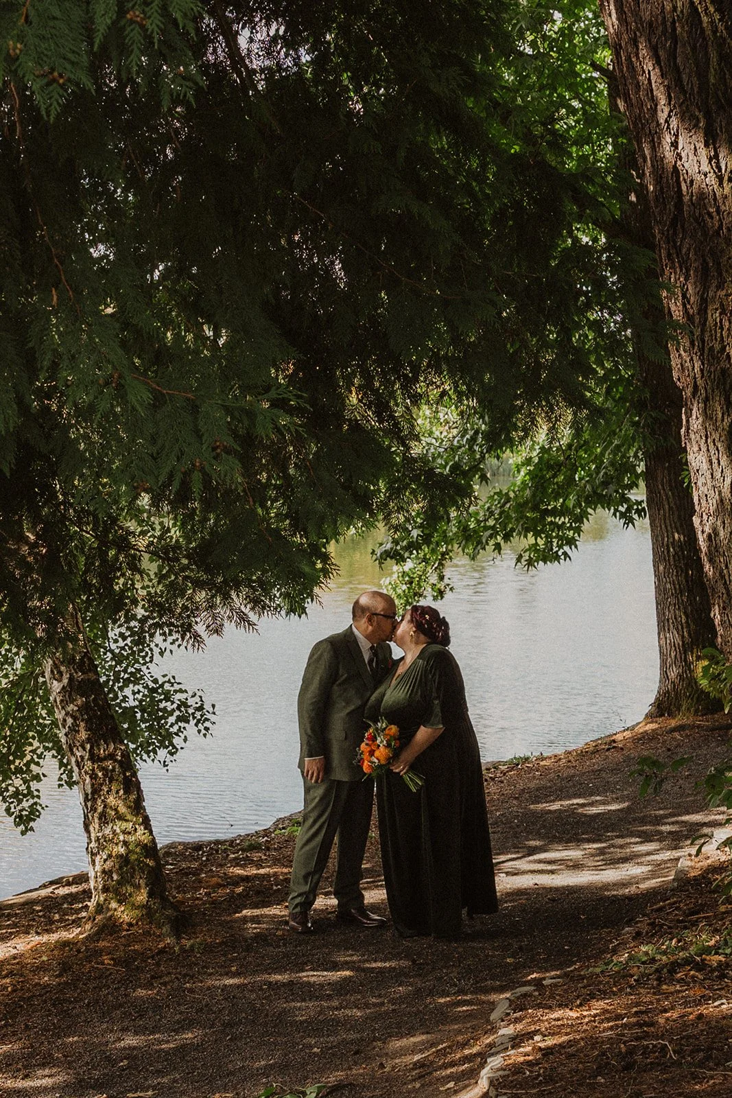Trailing willow branches frame a couple portrait beside the Crystal Springs lake