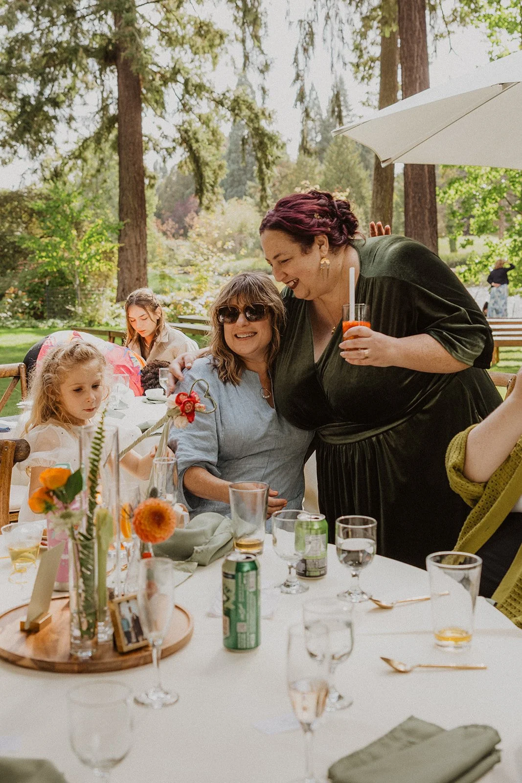 Bride in green velvet talking with guests beside a rhododendron after the ceremony