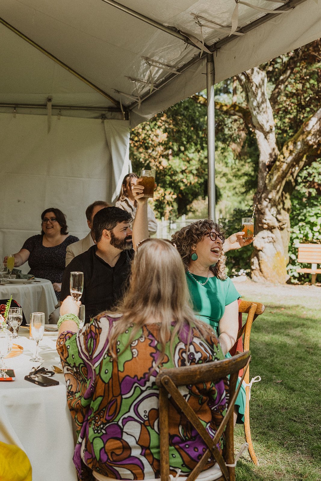 Guests raise glasses for a toast under the tent at an outdoor reception