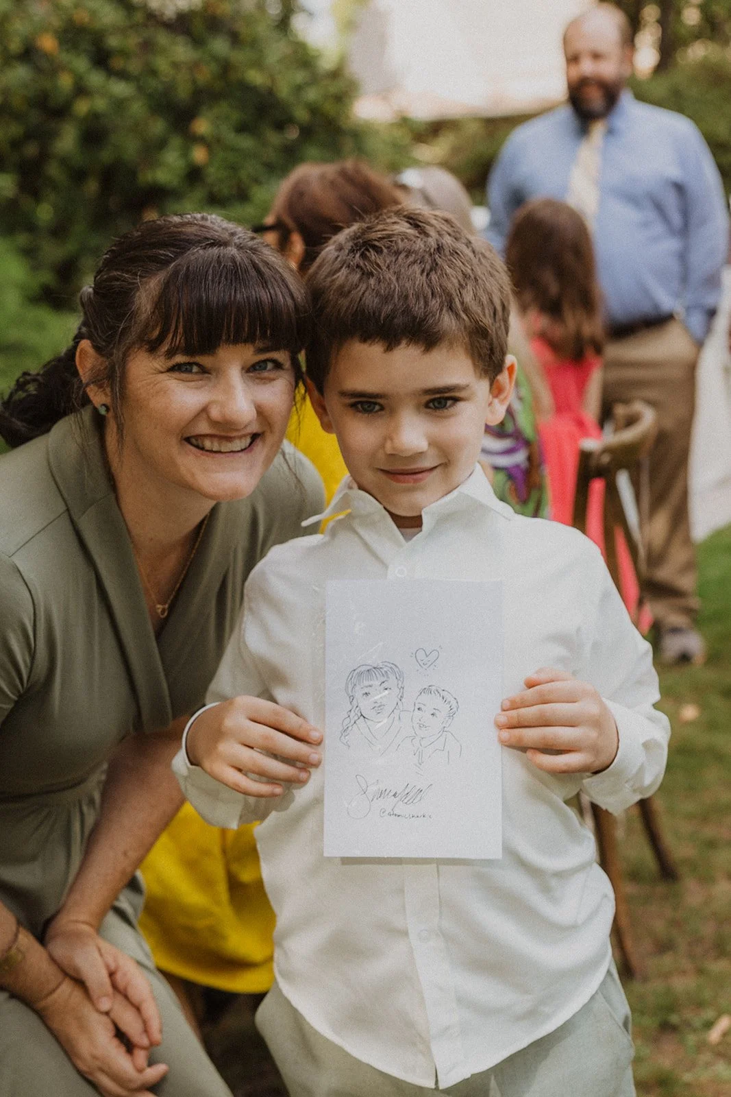 Young guest holds up the illustration drawn for him during the reception