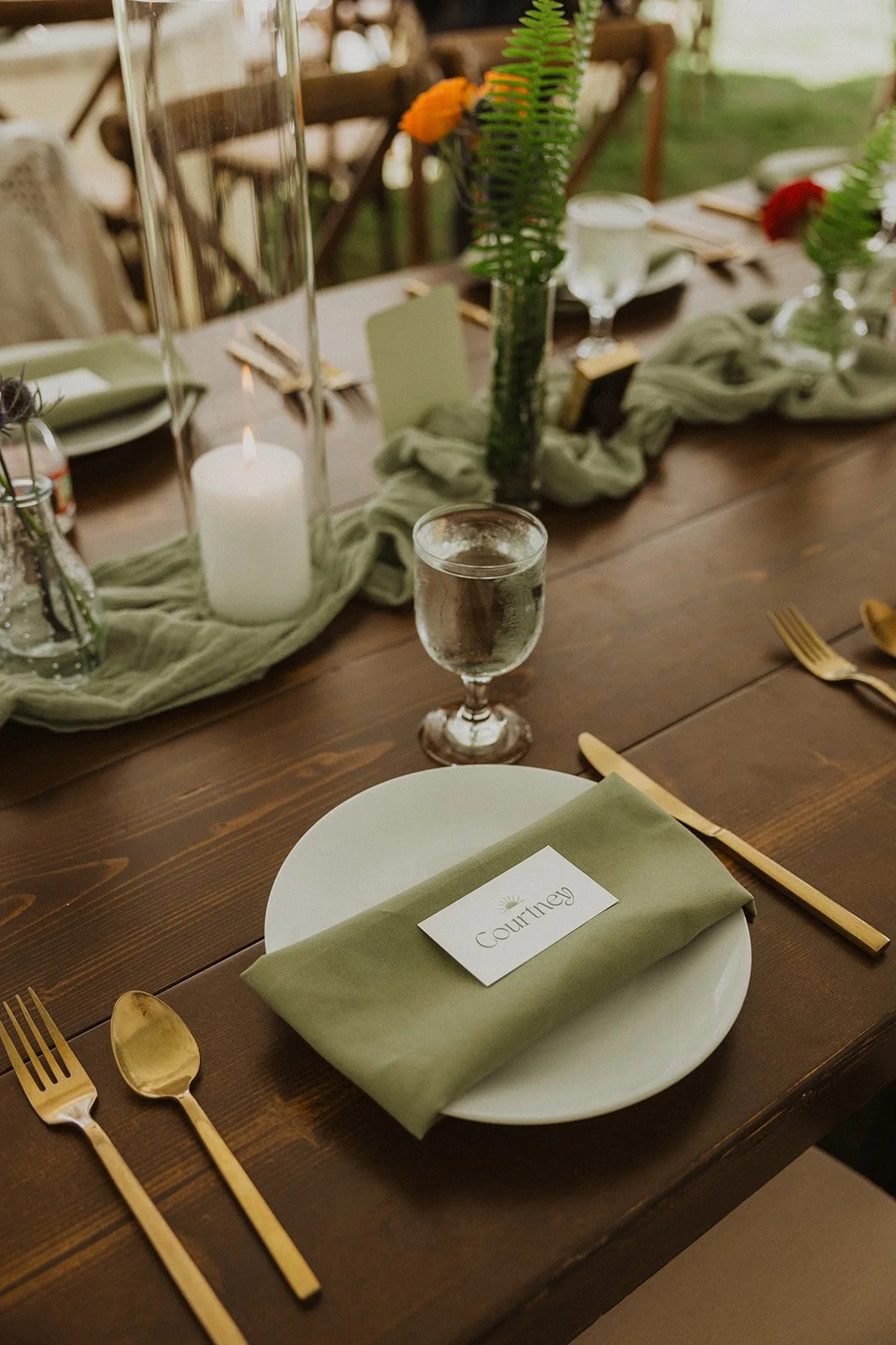 Place setting with a sage napkin, gold flatware and a printed name card