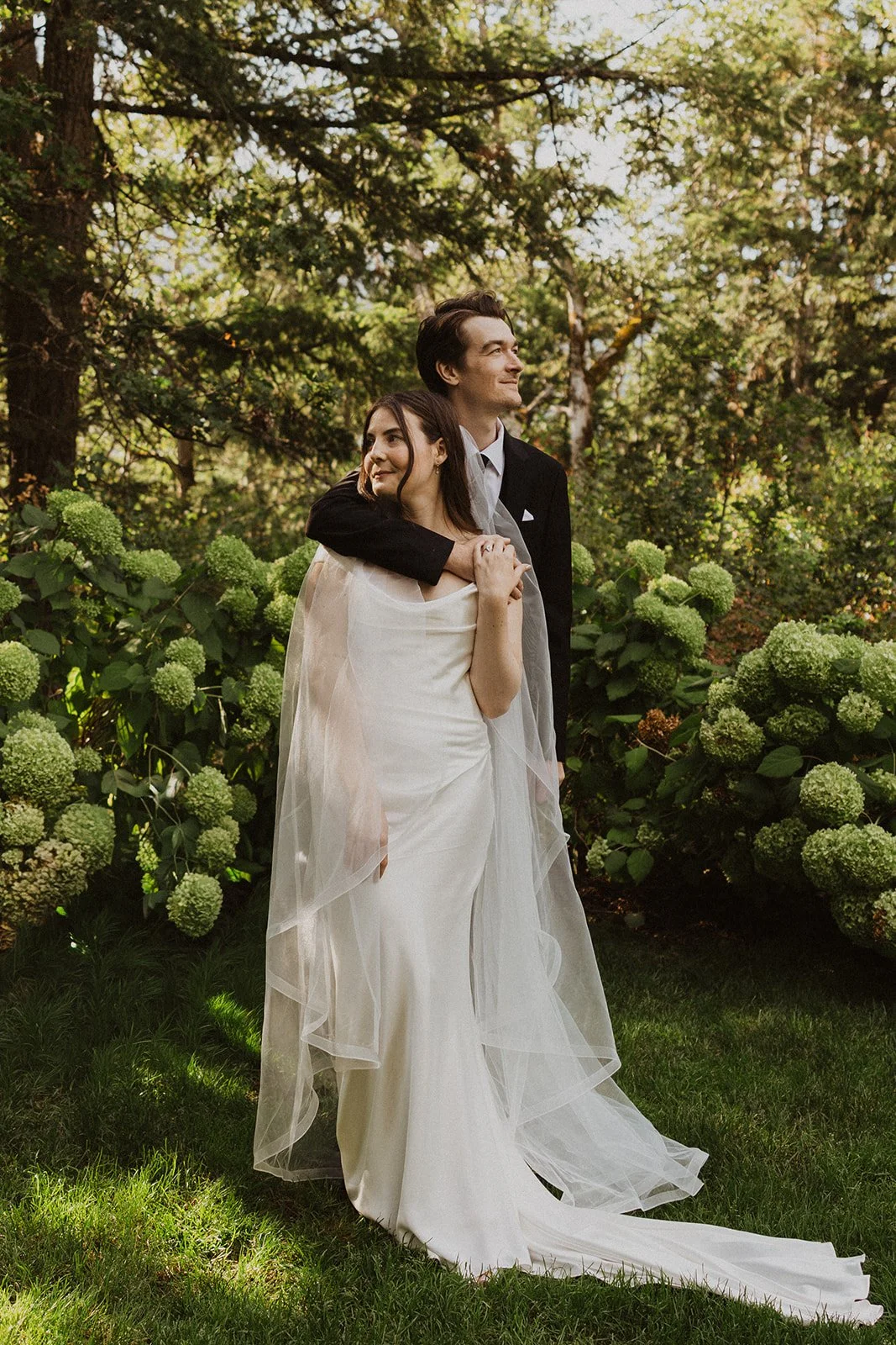 Veil and train spread across the lawn at a forest micro wedding