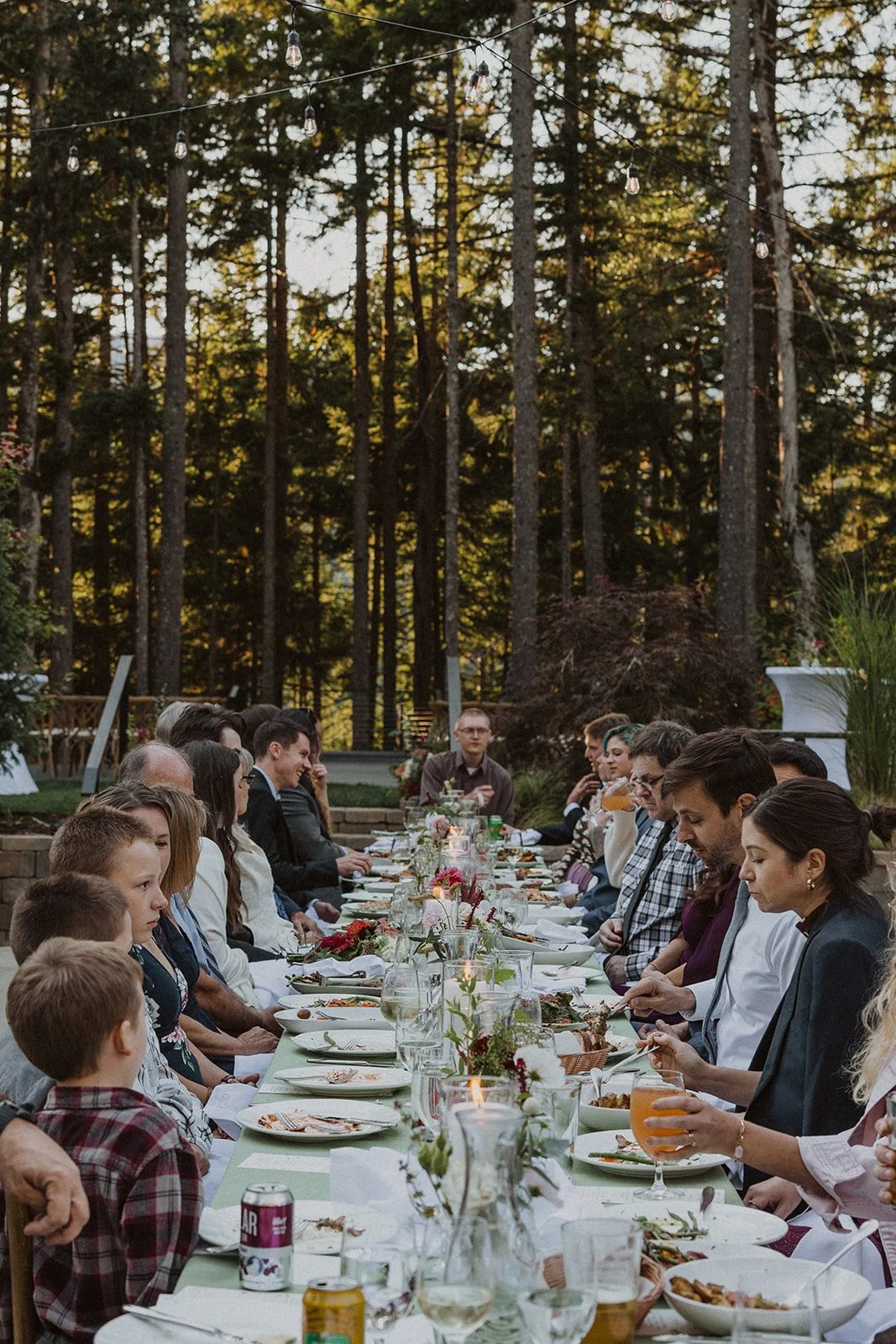 One long table under string lights and tall trees in the Columbia River Gorge