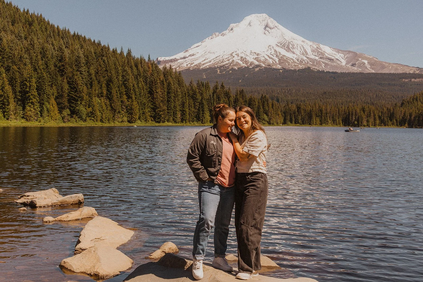 Cheek to cheek on the rock above the water in Trillium Lake engagement photos