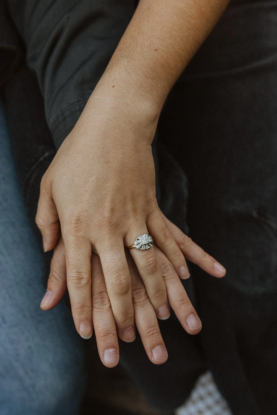 Vintage gold ring with a diamond cluster resting on two stacked hands