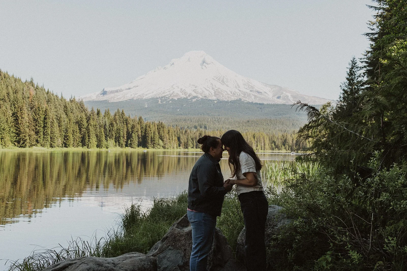 Foreheads together by the water in Trillium Lake engagement photos
