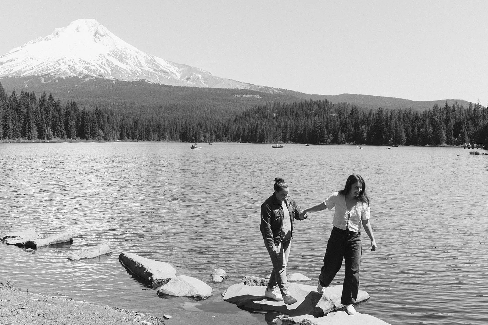 Crossing the stepping stones hand in hand with Mount Hood behind them