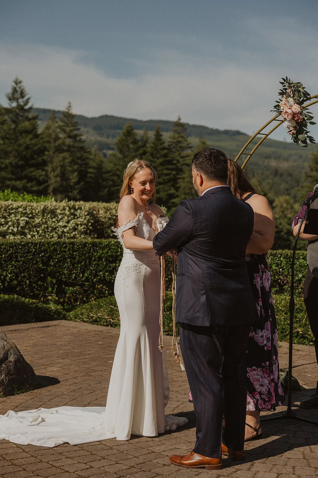 Hands bound together with cord during a handfasting in front of mountains
