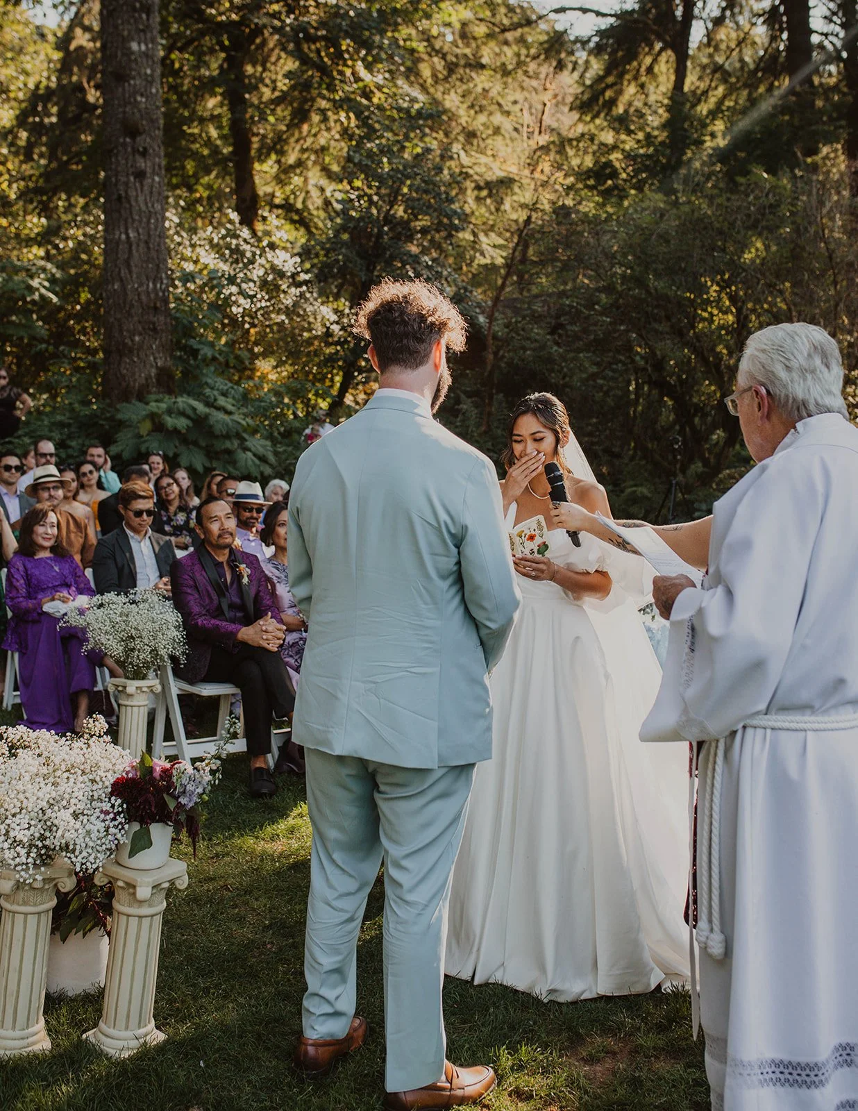 Covering her mouth laughing partway through vows at the lakeside ceremony